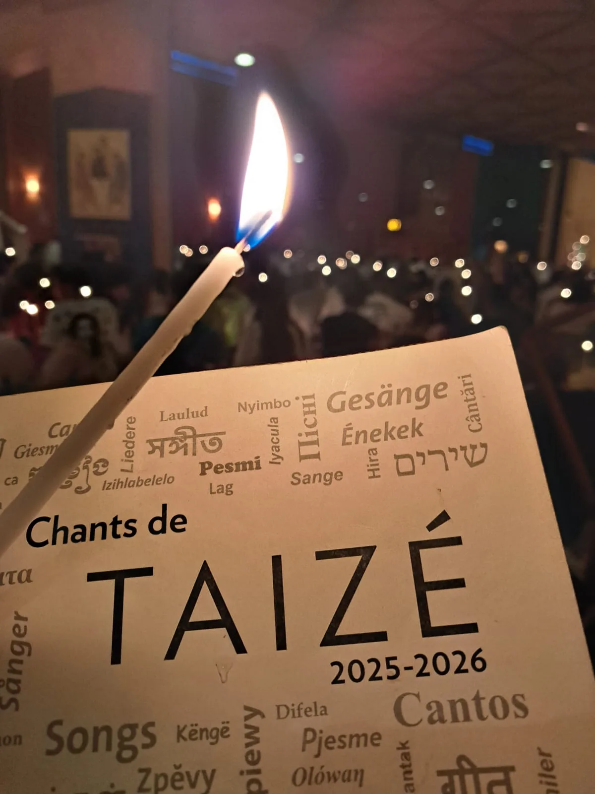 Kerze auf dem Liederheft „Chants de Taizé“ beim abendlichen Lichtergebet